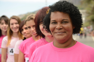 line of women of varying ages and races standing in a line, all wearing pink shirts